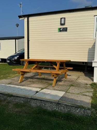 a wooden picnic table in front of a trailer at Modern Caravan 2 Bedrooms Sleeps 6 near Weymouth in Wyke Regis