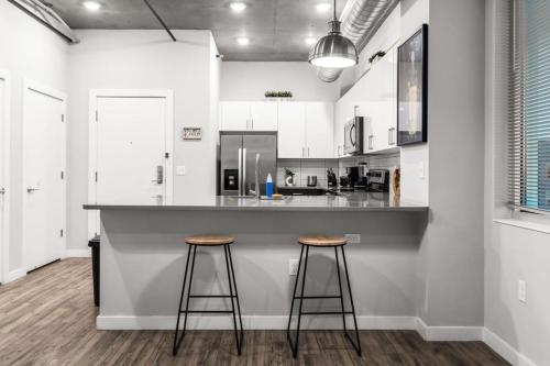 a kitchen with two bar stools at a counter at Modern 2 Bed Getaway Steps from Tropicana Field in St. Petersburg