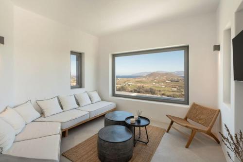 a living room with a white couch and a large window at Sunrise Poem Villa 1 in Prodromos Paros