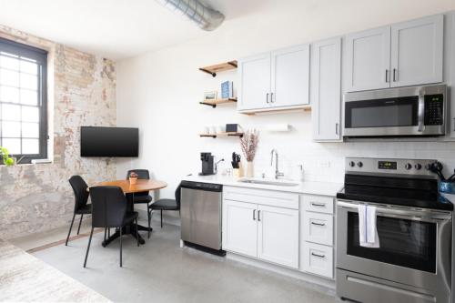 a kitchen with white cabinets and a table with chairs at Brewery District 2-Story 2BR Apt Near Fiserv with Rooftop, Gym, and Parking in Milwaukee