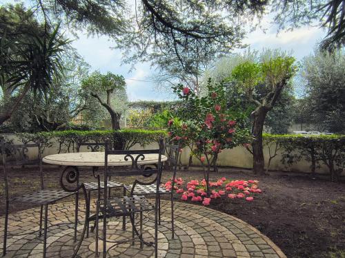 a table and chairs in a garden with flowers at Casa Vacanze Parco Azzurro - Il tuo angolo di tranquillita' ai Castelli Romani in Monte Compatri