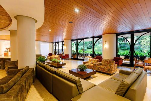 a large living room with couches and tables and windows at Panorama Hotel in Águas de Lindóia
