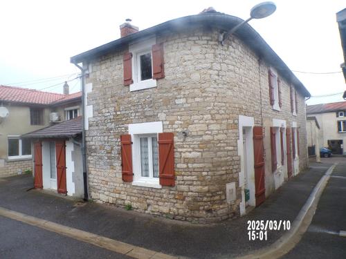 ein altes Backsteingebäude mit roten Rollläden auf einer Straße in der Unterkunft chambre chez l'habitant chez myriame in Eurville