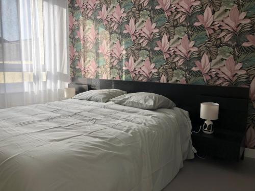 - une chambre avec un grand lit et du papier peint floral dans l'établissement Le Voyageur Sur le sable du samedi au samedi pendant les vacances scolaires, à Berck-sur-Mer