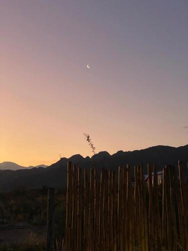 a fence in front of a sunset with the moon at Cabaña Vista del Plata in Las Compuertas