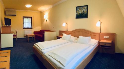 a hotel room with a bed and a red couch at Hétkúti Wellness Hotel in Mór