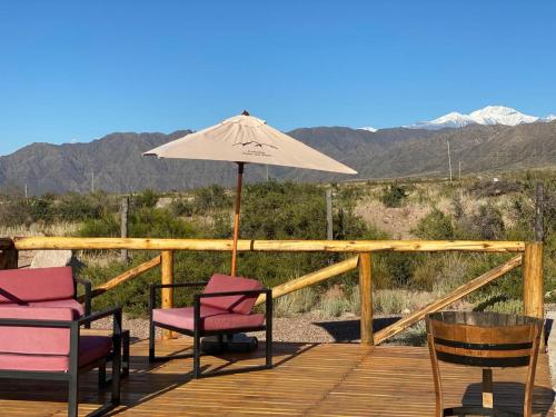 a deck with two chairs and an umbrella at Cabaña Vista del Plata in Las Compuertas