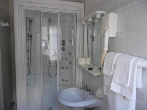 a white bathroom with a shower and a sink at Hotel Ristorante La Ginestra in Recanati
