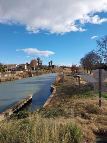un pont sur une rivière avec un panneau à côté de celle-ci dans l'établissement Appartement centre ville 2 chambres, à Sérignan