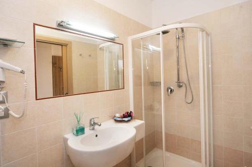 a bathroom with a sink and a shower with a mirror at Hotel Riva dei Cavalleggeri in Marina di Bibbona