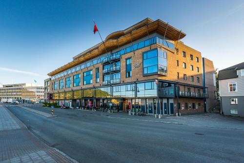 a building with a flag on top of it on a street at Thon Hotel Harstad in Harstad