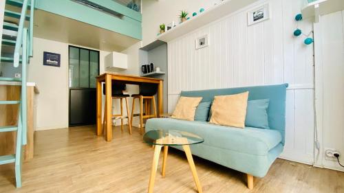 un salon avec un canapé bleu et une table dans l'établissement L Appart’ Grande Plage, à Les Sables-dʼOlonne