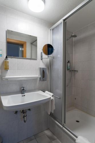 a white bathroom with a sink and a shower at Waldhotel Geländer in Schernfeld