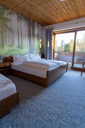 a large bedroom with two beds and a large window at Waldhotel Geländer in Schernfeld