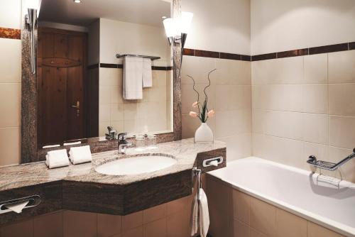 a bathroom with a sink and a bath tub at Hotel Waldhuus in Davos