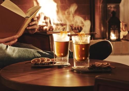 a person reading a book and two glasses of beer on a table at Hotel Waldhuus in Davos