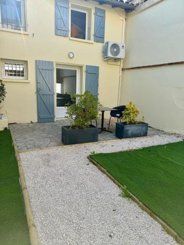 a patio with two plants and a table in front of a house at Le patio, T2 en centre ville in Montauban