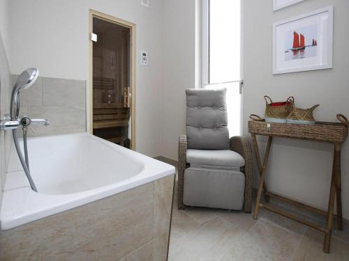 a bathroom with a bath tub and a chair at Ferienhaus Fiete in Lancken in Lancken