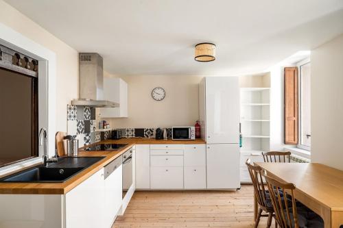 une cuisine avec des armoires blanches et une table en bois dans l'établissement Le Corsaire de Solidor Studio, à Saint-Malo