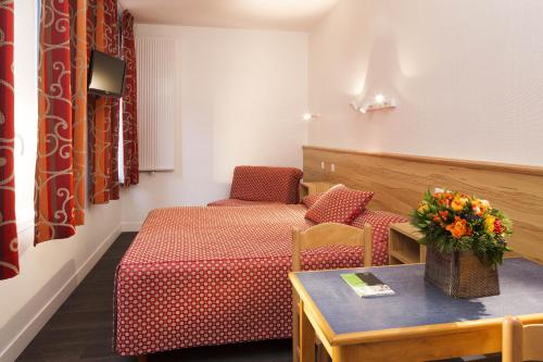um quarto de hotel com uma cama e uma mesa com flores em Family Residence em Paris