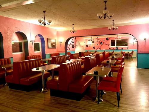 a restaurant with red chairs and tables in a room at Café Retro Brøns Kro in Skærbæk