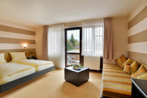 una camera d'albergo con letto e divano di Hotel am Brenner a Tauberbischofsheim