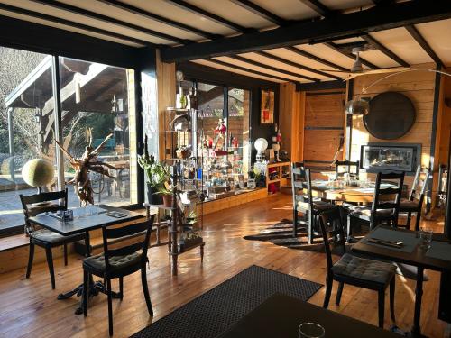 une salle à manger avec des tables et des chaises ainsi qu'une grande fenêtre dans l'établissement Un nid de verdure 1 ch, à Sirod