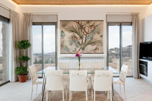 a dining room with a glass table and white chairs at Villa Galli & Leo in Jbeil