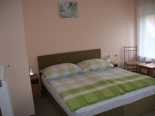 una camera da letto con un letto con una coperta verde e bianca di Margitapartman a Bük