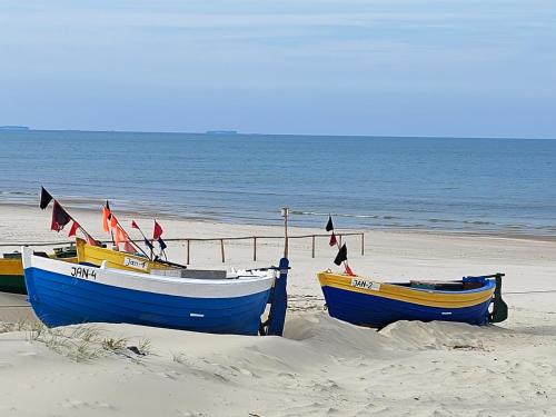 three boats sitting on the sand on the beach at Chaty Sielanka in Junoszyno
