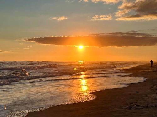 a sunset on the beach with people walking in the water at Private Beach-Private Pool-Easy walk to the Beach in Gulf Highlands