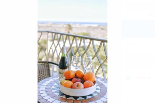 a table with a bowl of fruit and two wine glasses at Caesarea Vacation Rooms in Caesarea