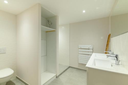 a white bathroom with a toilet and a sink at Maison, 150 m de la plage, la Tresson,Noirmoutier in La Guérinière