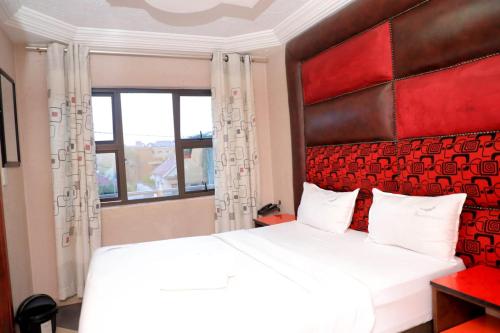 a bedroom with a large white bed with a red headboard at Yeoville Hotel in Johannesburg