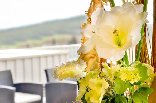 a vase filled with white and yellow flowers at Hotel am Brenner in Tauberbischofsheim