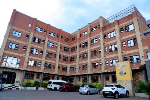 a large brick building with cars parked in front of it at Yeoville Hotel in Johannesburg