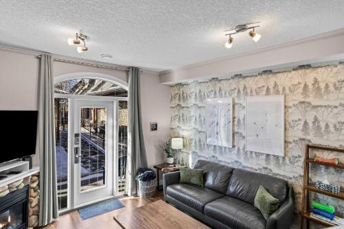 a living room with a couch and a tv at Cozy Mountain Chalet at Mystic Springs with Pool & Hot Tub Access in Canmore