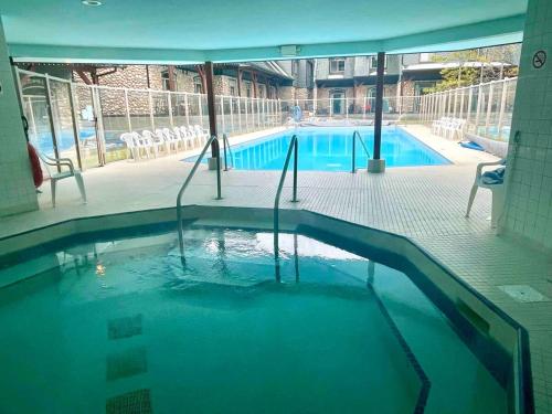 a swimming pool with blue water in a building at Cozy Mountain Chalet at Mystic Springs with Pool & Hot Tub Access in Canmore