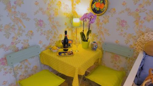 a yellow table with two chairs and a table with a bottle of wine at Apartament - Lisa in Budva
