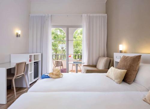 a bedroom with a large white bed and a window at Sol Falco Menorca in Son Xoriguer