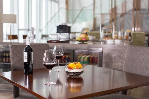 a table with two glasses of wine and a bowl of fruit at Pullman Changshu Leeman in Changshu