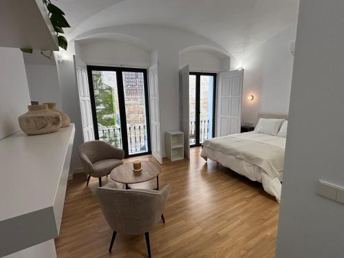 a white bedroom with a bed and a table and chairs at La Pata Suites in Trujillo