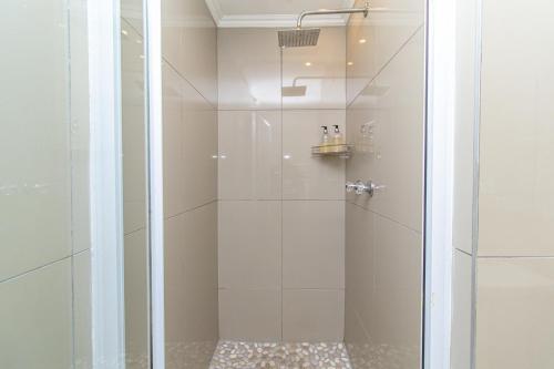 a shower with a glass door in a bathroom at Modern Seaview Apartment in Summerstrand