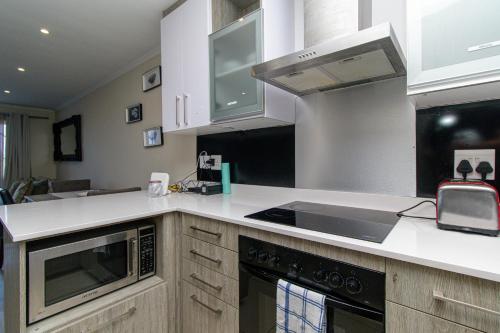 a kitchen with white cabinets and a stove top oven at Modern Seaview Apartment in Summerstrand