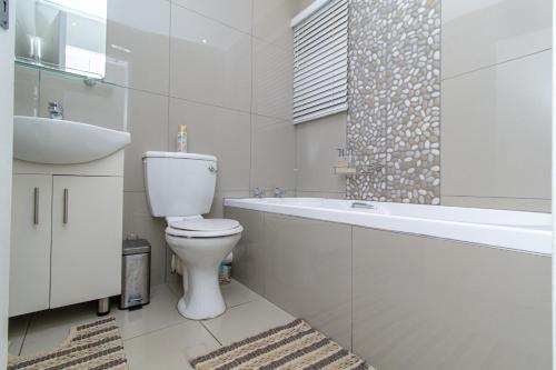 a bathroom with a toilet and a tub and a sink at Modern Seaview Apartment in Summerstrand