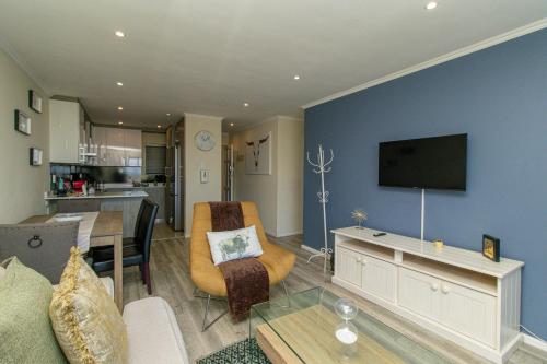 a living room with a tv on a blue wall at Modern Seaview Apartment in Summerstrand