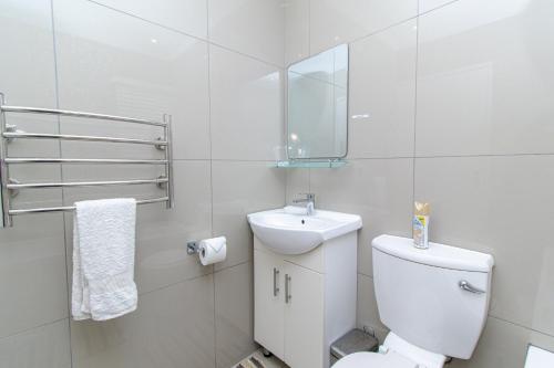 a white bathroom with a toilet and a sink at Modern Seaview Apartment in Summerstrand