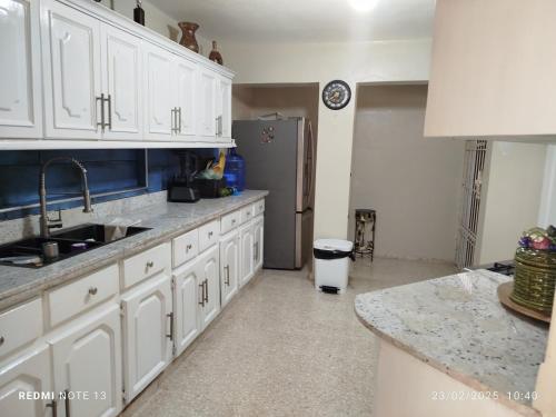 Una cocina con gabinetes blancos y un refrigerador de acero inoxidable. en Residencial Oasis, en Juan López