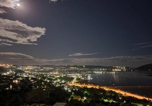 a view of a city at night with the moon at Lagoon Studio - Maison Mahogany - design meets breathtaking views of lagoon in Knysna