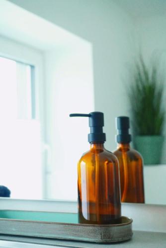 two bottles of essential oils sitting on a window sill at Ferienwohnung KÖÖK Heimathafen - Modern, Balkon, Strandnah in Neuharlingersiel